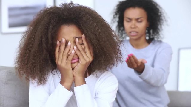 Sad teen african girl upset by strict mum scolding daughter