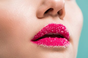 cropped view of woman with sugar on lips isolated on blue