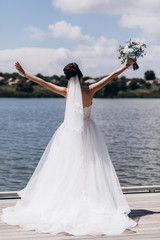 Fototapeta na wymiar Bride in white wedding dress with a beautiful bouquet of roses