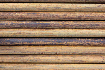 Obraz premium Rusty grunge pipes horizontal background. Orange corrosion rust on steel metal factory industrial pattern. Rough texture brown parallel stack close up