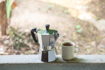 The moka pot is a stove-top or electric coffee maker and a cup of coffee , background 