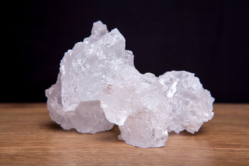 Coarse granules of natural rock or sea salt on a rustic old wooden table.