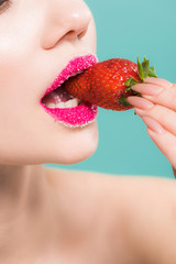 cropped view of woman with sugar on lips eating tasty strawberry isolated on blue