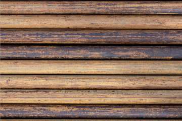 Rusty grunge pipes horizontal background. Orange corrosion rust on steel metal factory industrial pattern. Rough texture brown parallel stack close up