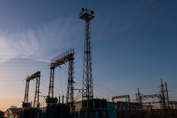 Caution high voltage. The tower and high-voltage towers are blurred in the background. Evening or morning sky. Silhouette.