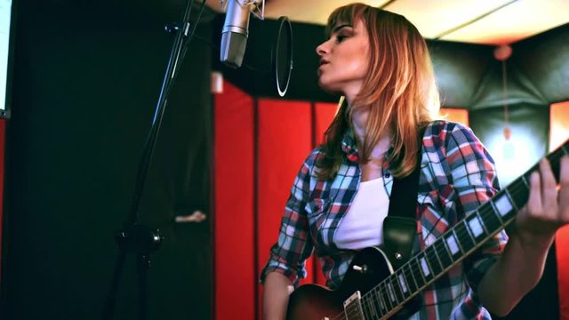 Young singer with guitar singing a song in recording studio