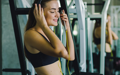Fototapeta na wymiar Active girl using smartphone in fitness gym. Young woman workout in gym healthy lifestyle. Young woman using phone in gym. Change for health concept.