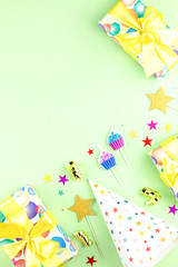 Birthday party background with wrapped gifts, confetti, party hats, decorations, top view