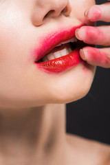 Naklejka premium cropped view of young woman removing red lipstick isolated on black