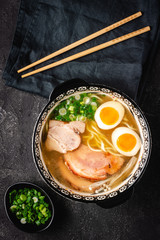 Japanese Ramen Soup with Udon Noodles, Pork, Eggs and Scallion on dark Stone Background - 267979541