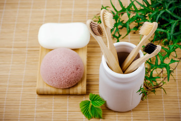 Bathroom essentials.  natural four bamboo toothbrushes in ceramic dish on bamboo background. lifestyle concept. zero waste at home