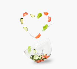 glass salad bowl in flight with vegetables: tomato, cucumber and leaf salad. Isolated on white background. healthy diet