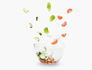 glass salad bowl in flight with vegetables: tomato, cucumber and leaf salad. Isolated on white background. healthy diet