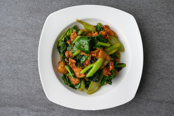 Fried Chinese kale with crispy skin chicken in oyster sauce and chilli in the white dish.