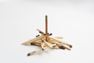 A pile of burnt matches, among which one is not burnt. On a white background.