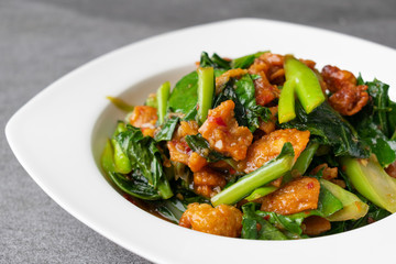 Fried Chinese kale with crispy skin chicken in oyster sauce and chilli in the white dish.
