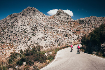 Man and woman ride together on road bicycle. Adventure in big mountains