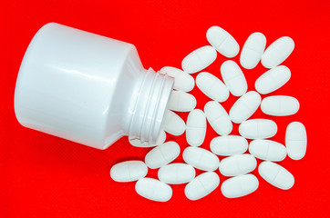 white tablets on a red background and a container for their storage - 267982313