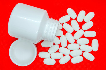white tablets on a red background and a container for their storage - 267982361