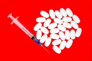 white tablet and disposable syringe on a red background - 267982524