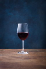 Glass of red wine on wooden table. Blue background. Copy space.