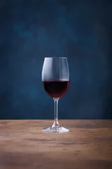 Fotobehang Glass of red wine on wooden table. Blue background. Copy space. © annapustynnikova