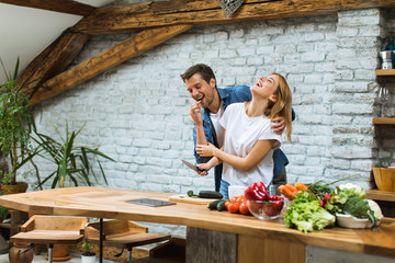 Lovely cheerful couple cooking dinner together and having fun at rustic kitchen