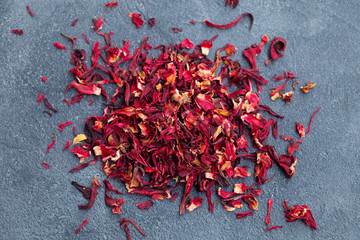 Hibiscus flower tea scattered on grey stone background. Copy space. Top view.