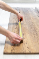 Man using roulette tape and checking size of wooden table top