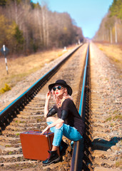 Naklejka premium traveling beautiful woman with retro suitcase waiting for a train 