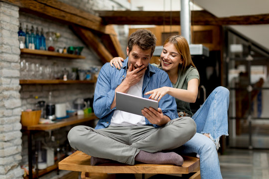 Young couple is using a digital tablet and smiling in kitchen at home