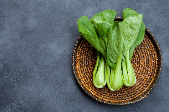 Bok choy fresh salad on wooden plate. Grey background. Top view. Copy space.