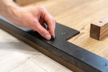 Fototapeta na wymiar Man using screw fasten metal element on wooden table top
