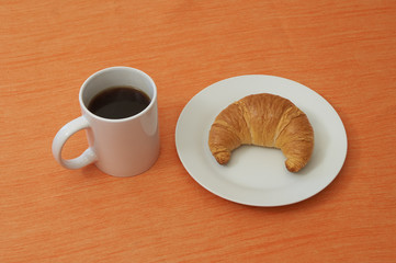 Kaffe und Croissant auf orangem Untergrund