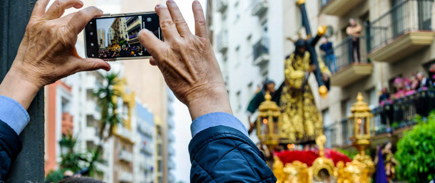A man keeps on his mobile phone the image of the step of the Procession of Jesus the Nazarene in Huelva, Spain.