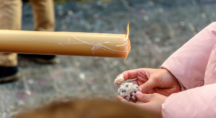 A little girl makes a small ball of wax, dripping from a candle in a procession of Holy Week in Huelva, Spain.