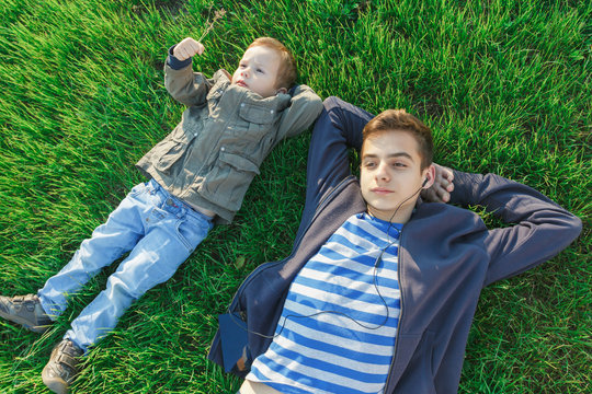 Two brothers, children and teenagers having fun, green meadow