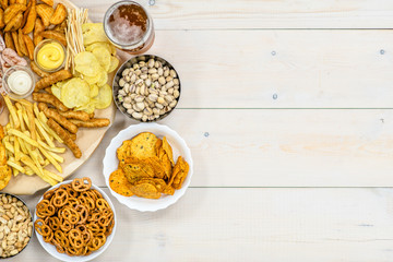 Mix of snacks with beer on light wooden background. Top view. Empty space for text