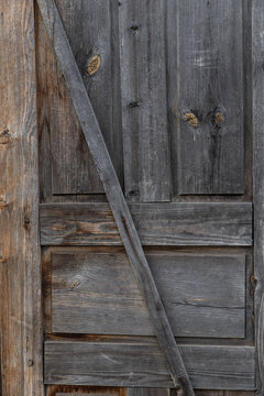 Part of the door. Old closed wooden door. A peeling, cracked, light brown door.
