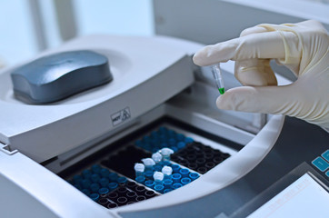 Scientist holding PCR tube put into PCR machine
