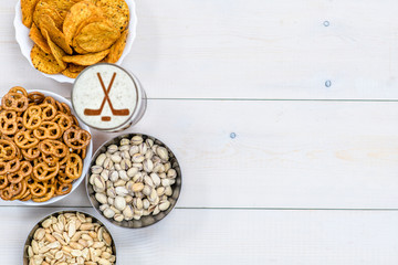 Beer with silhouettes of hockey sticks on beer foam and snacks on wooden background. Empty space for text