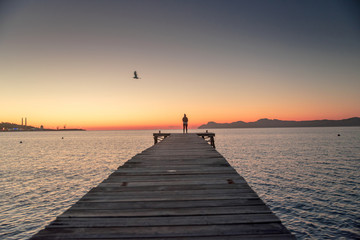 Naklejka na ściany i meble Woman standing alone on the pier
