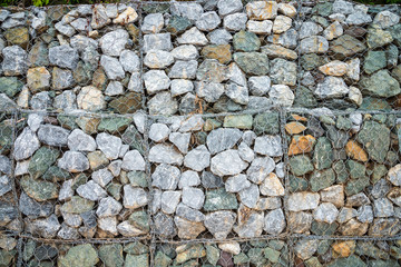 Gabion protection wall, rock stone In steel wire mesh against falling rock from mountain into road. Abstract surface texture background.