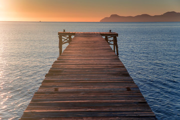 Fototapeta na wymiar Pier in beautiful summer sunrise light. Warm orange colors, Mallorca, Spain