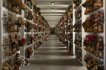 Viale di tombe con fiori per i defunti all'interno di un cimitero