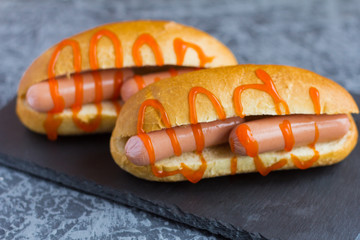 fresh hot dogs with sharp ketchup on a stone Board