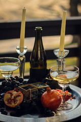pomegranate, wine and candles on a tray with jewelry and caskets. Gothic still life on the street. Sliced pomegranate on a silver tray