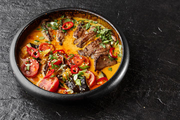 Kaeng Pled Ped Yang (Roasted Duck in Red Curry) , with rice. Thai cuisine. Restaurant, lunch, dinner. View from above. black stone background