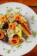 Salad with fresh salmon on a white plate close-up