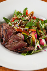 Close-up salad with grilled pork steak on a white plate